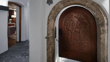 Un pasillo con una gran puerta de madera adornada con tallado intrincado, que da a una escalera.