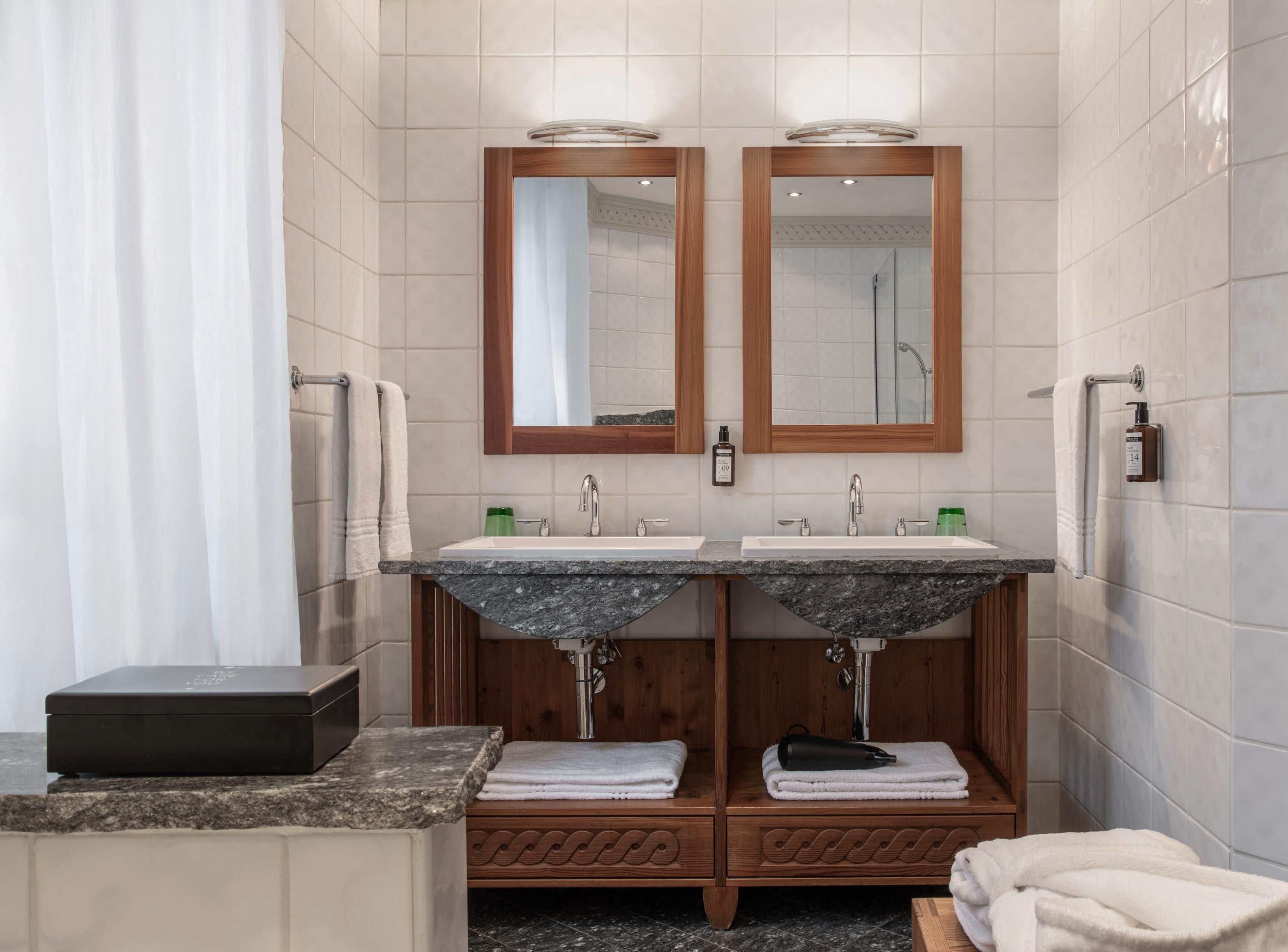 Un baño moderno con dos lavamanos, tocador de madera y ducha.