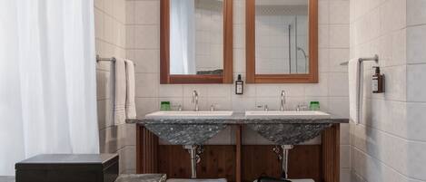 A modern bathroom with two sinks, wooden vanity, and a shower.