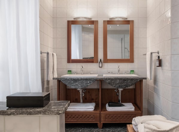A modern bathroom with two sinks, wooden vanity, and a shower. - Hotel Schwarzer Adler (Innsbruck)