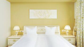 A hotel room with a large bed, two bedside tables with lamps, a decorative headboard, and a painting on the wall.