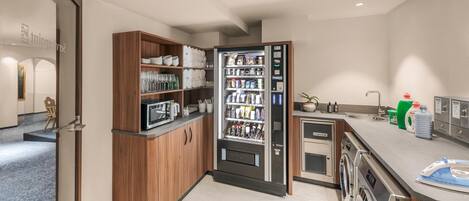 Una cucina compatta con forno a microonde integrato, un mini-frigo fornito di bevande e una lavatrice.