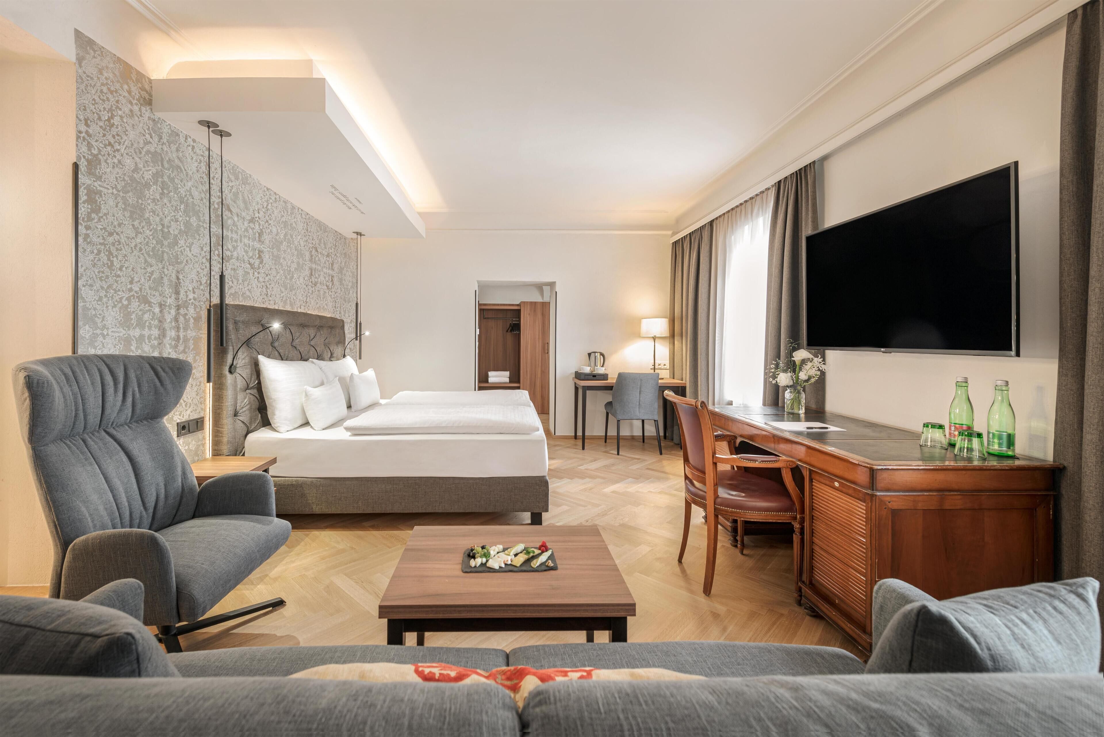 Een hotelkamer met een bed, bureau, televisie en zithoek.