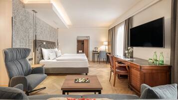 Een hotelkamer met een bed, bureau, televisie en zithoek.