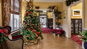 A grand hallway with a large Christmas tree, elegant chandeliers, and a red carpet leading to a dining area. - The Glidden House (Cleveland)