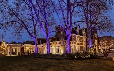 A large, historic building with multiple windows and a well-maintained lawn.
