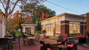 An outdoor patio with wicker furniture and string lights. - The Glidden House (Cleveland)