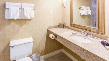 A bathroom with two sinks, a toilet, a trash can, and a mirror.