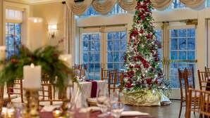A dining area with a Christmas tree, tables set for a meal, and large windows. - The Glidden House (Cleveland)