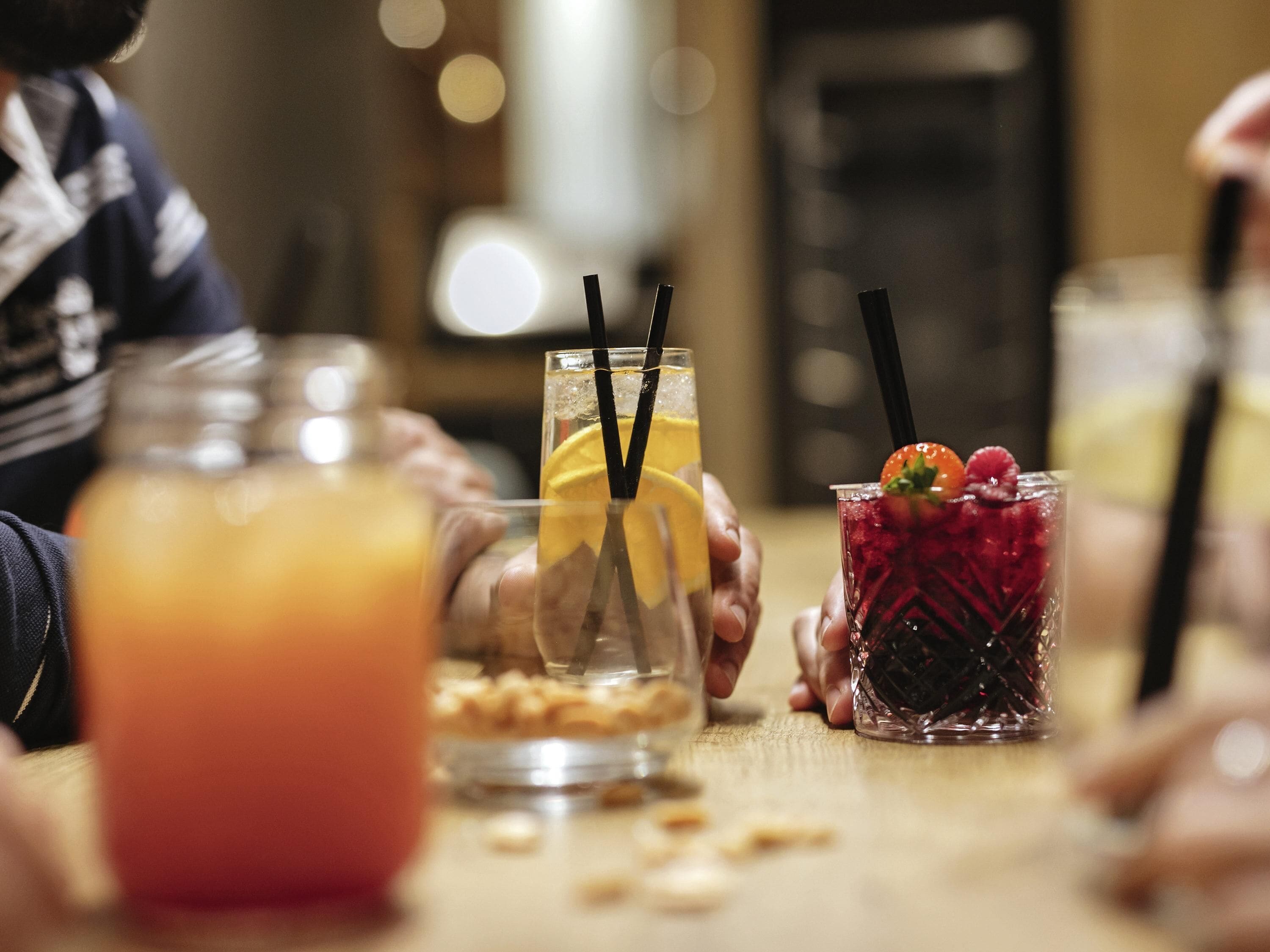 A table with three drinks, one with a lemon slice, another with a strawberry, and a third with a berry mix.