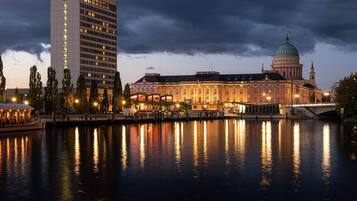 Ein historisches Gebäude mit einer Kuppel, ein modernes Hotel und ein Fluss, der die Bauten widerspiegelt.