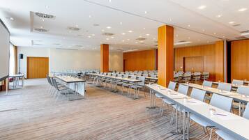 A conference room with long tables and chairs, wooden paneling, and recessed ceiling lights.