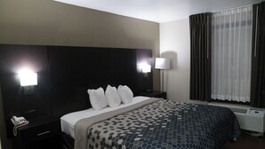 Una habitación de hotel con cama, lámparas de noche, teléfono y ventana con cortinas.