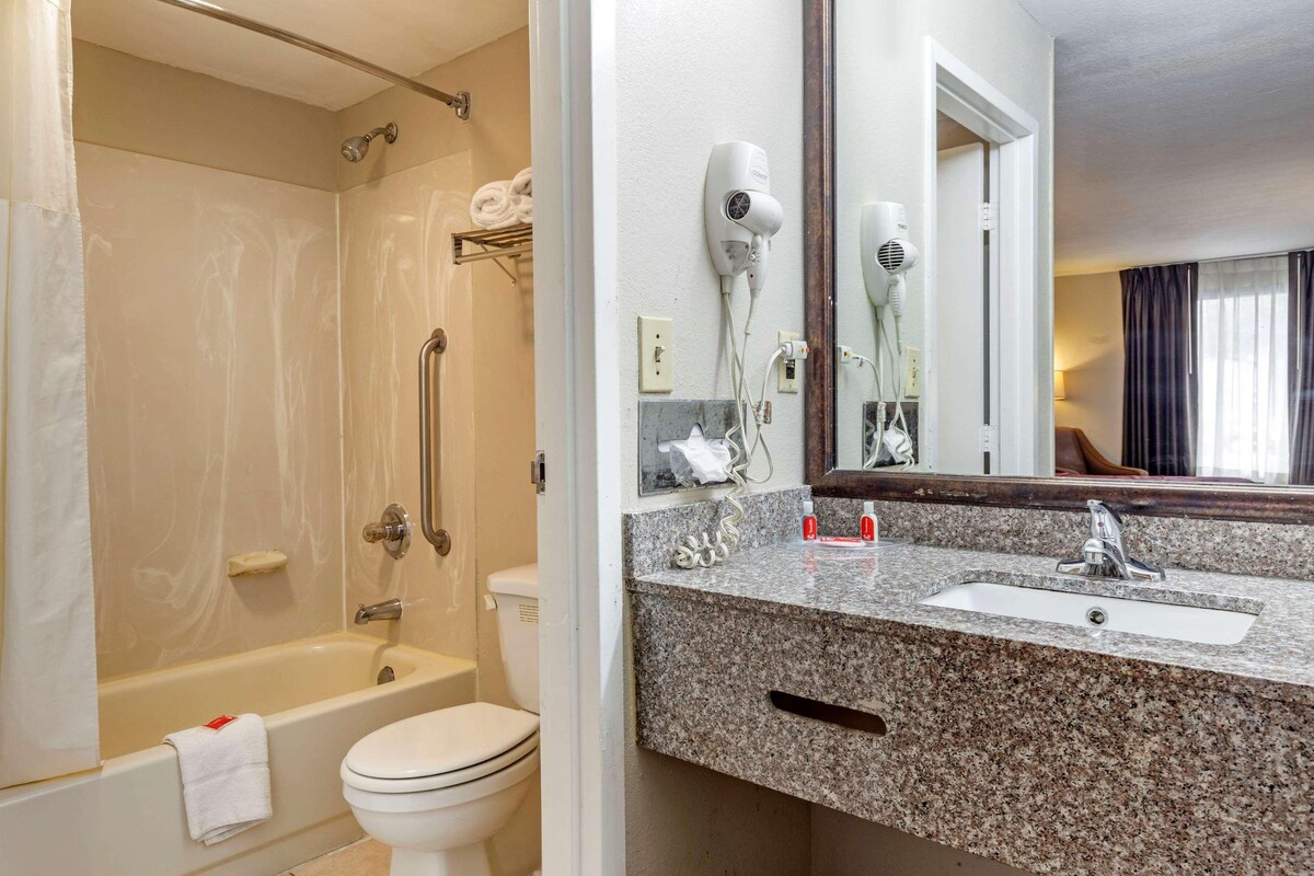 A bathroom with a bathtub, toilet, and a sink with a mirror.