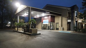 Un hotel Traveltodge con un acceso cubierto, zona de estar exterior y aparcamiento.