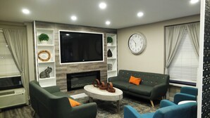 Una sala de estar moderna con una televisión de pantalla plana, sofás, una mesa de centro y una chimenea.