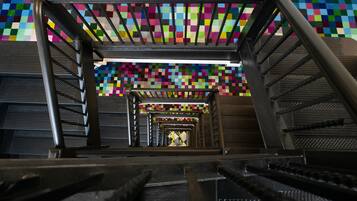 Una escalera con un techo de mosaico colorido y barandales de metal.