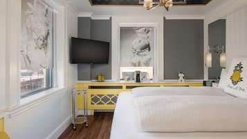 Ein Schlafzimmer mit einem großen Bett, einem Fernseher, Bildern an den Wänden und einem Fenster.