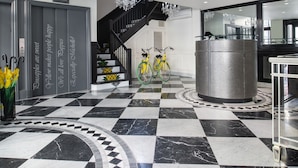 Un hall d’entrée avec un sol en marbre à carreaux, un comptoir d’accueil et deux vélos.
