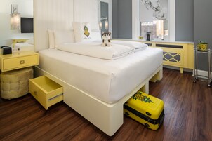A hotel room with a bed, a nightstand, a lamp, a suitcase, and a window with a view.