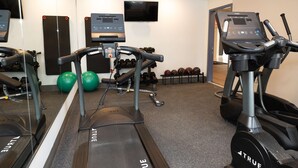 Un gimnasio con cintas de correr, mancuernas y pelotas de ejercicio.