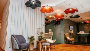 A modern hotel lobby with striped walls, wooden flooring, and multiple wicker chairs. - ibis Styles Luxembourg Centre Gare (Luxembourg City)
