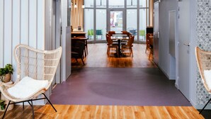 A modern interior with wicker chairs, a dining area, and a view through large windows. - ibis Styles Luxembourg Centre Gare (Luxembourg City)
