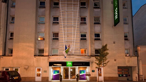 A hotel with a modern facade, multiple windows, and a prominent green flag. - ibis Styles Luxembourg Centre Gare (Luxembourg City)