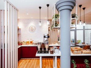 Une cuisine moderne équipée d’une machine à café, de fruits et d’un comptoir pour prendre le petit-déjeuner.