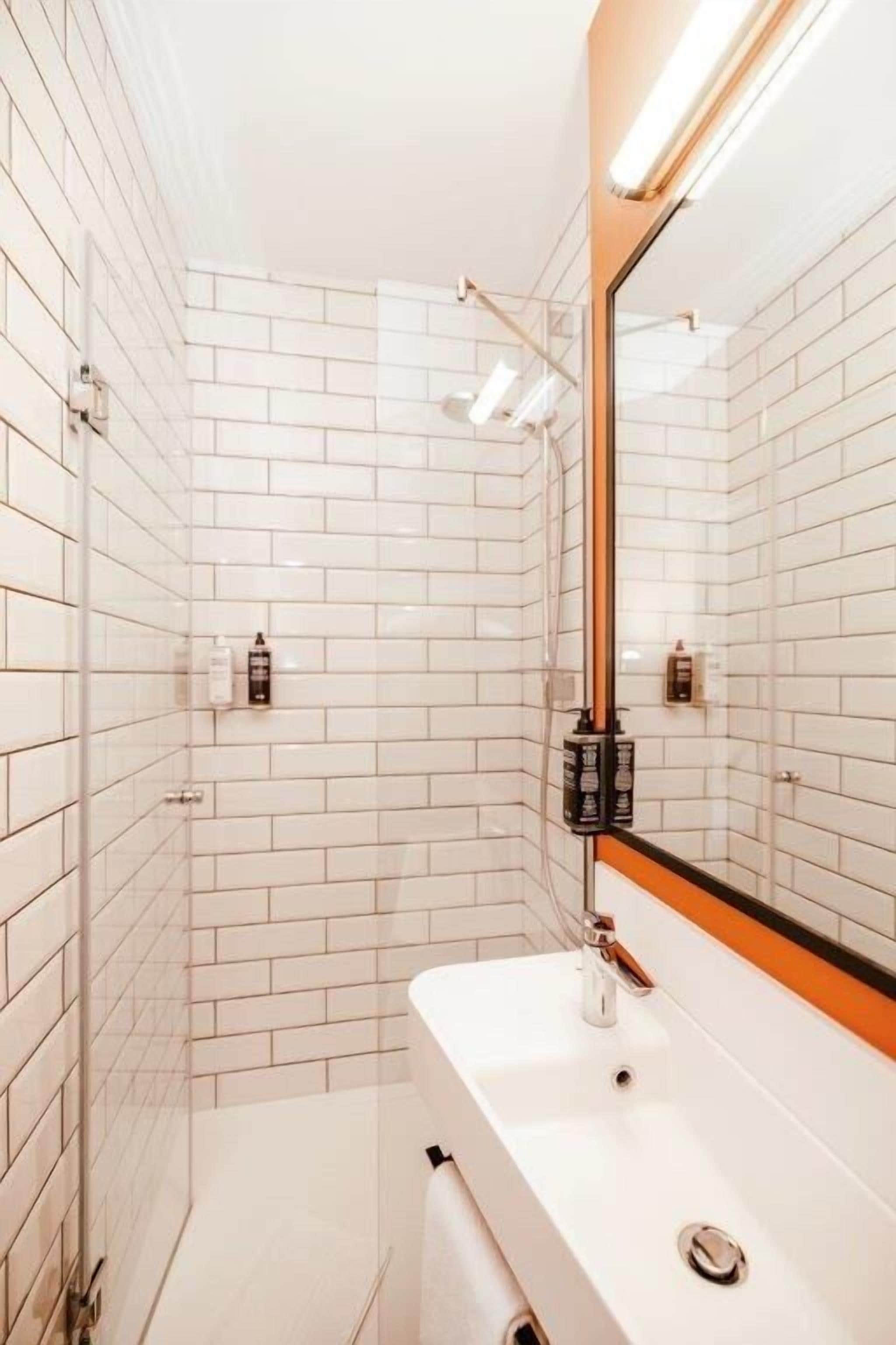 A modern bathroom with white subway tiles, a white sink, and a large mirror.
