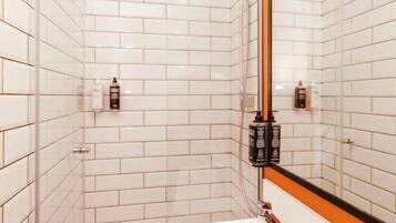 A modern bathroom with white subway tiles, a white sink, and a large mirror.