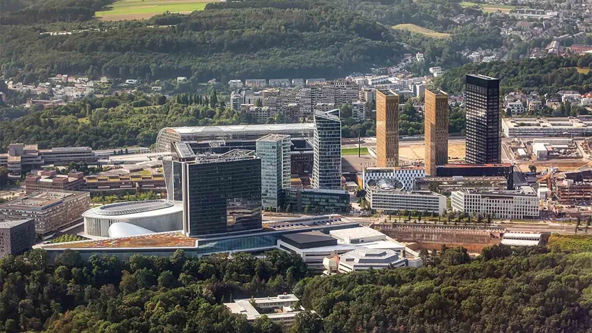 A modern urban area with high-rise buildings, a circular structure, and surrounding greenery.