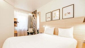 A hotel room with a large bed, a desk with a laptop, and a chair. There are three framed pictures on the wall. - ibis Styles Luxembourg Centre Gare (Luxembourg City)