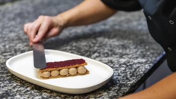 Una persona cortando un postre en capas sobre un plato blanco.