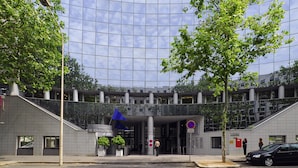 Un edificio moderno con fachada de vidrio, una escultura azul y un letrero que indica un cine.