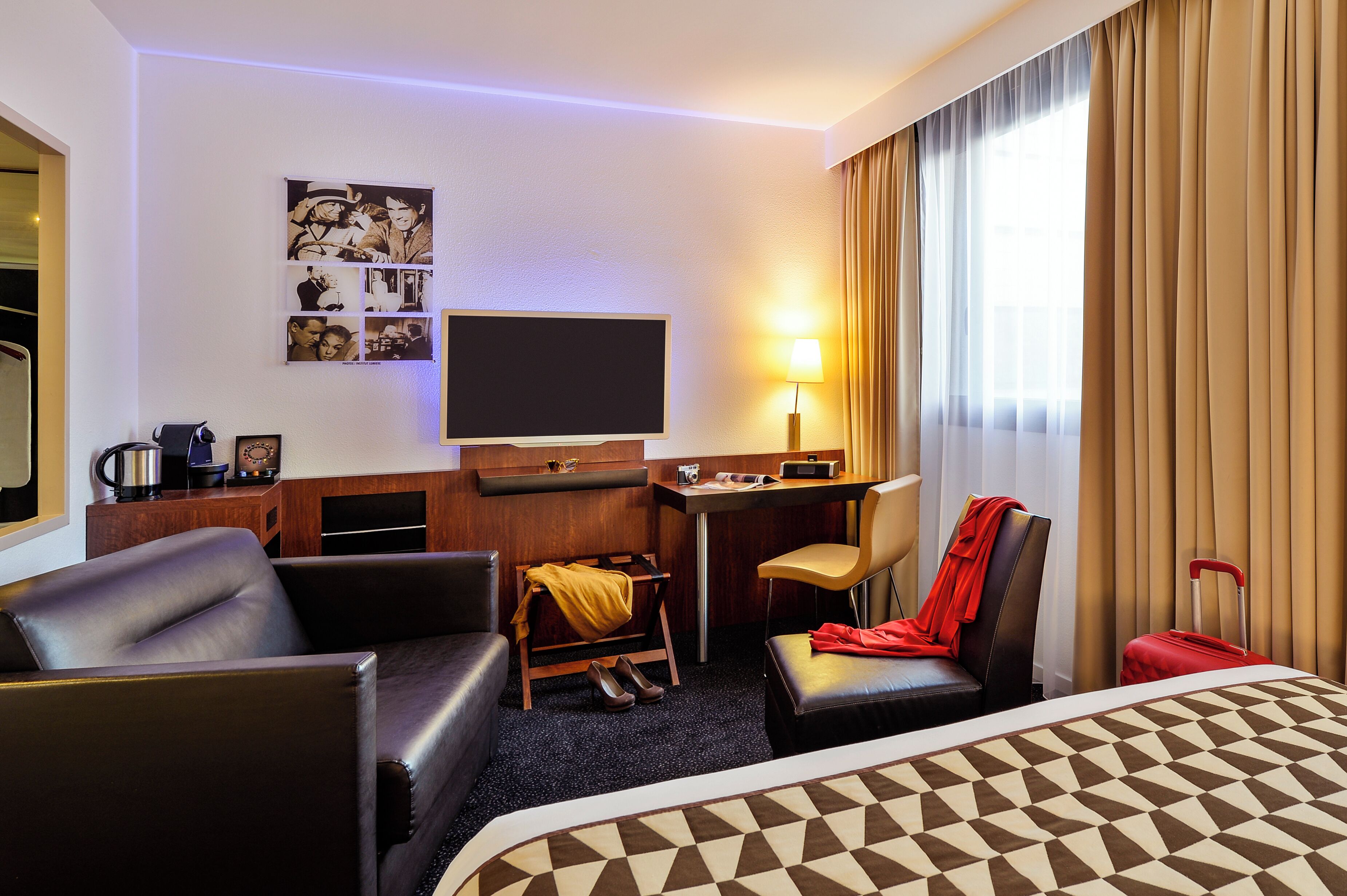 Una habitación de hotel con una cama, un escritorio, una silla, un sofá y una televisión.