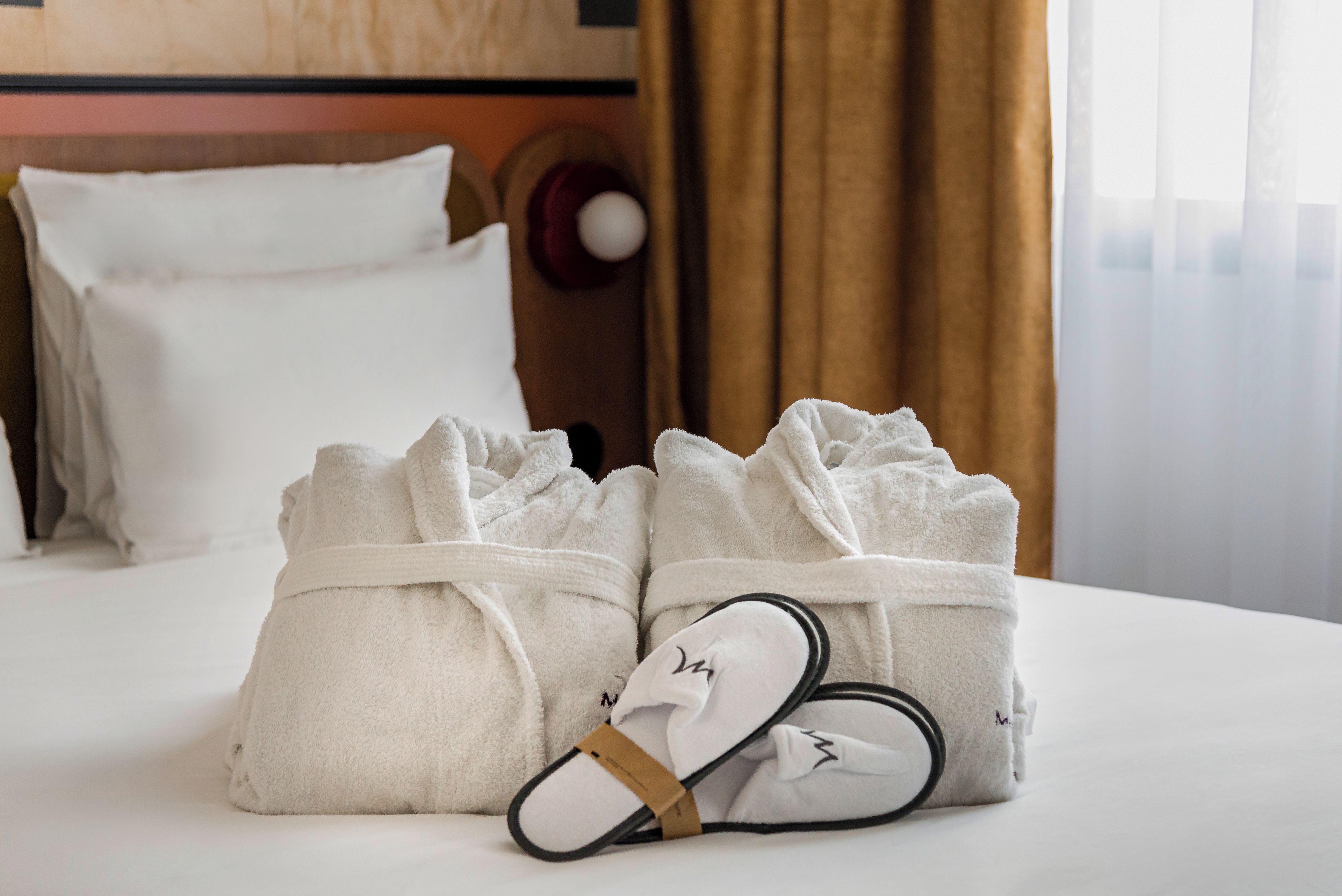 Un lit bien fait, avec deux serviettes pliées et une paire de chaussons.