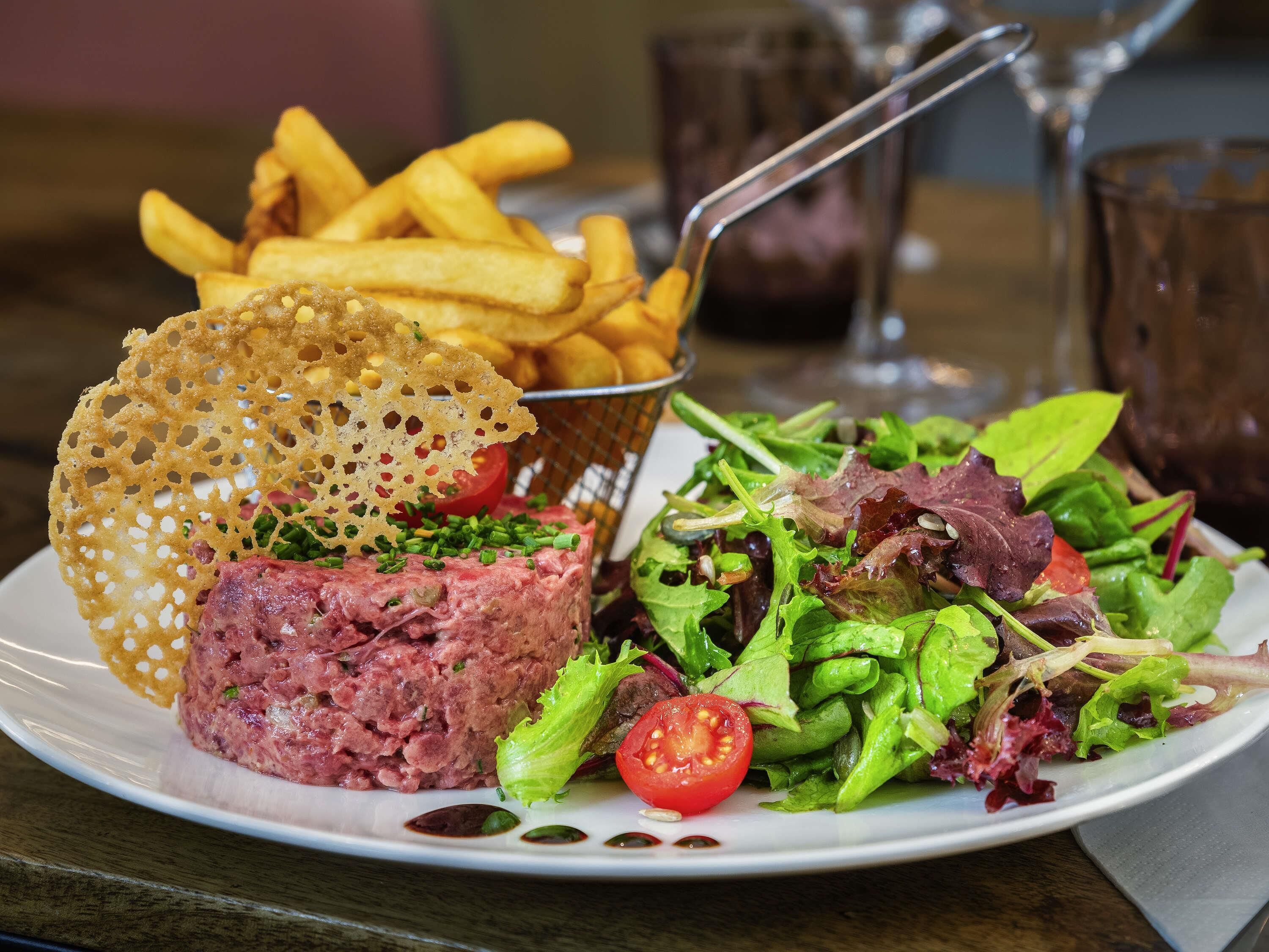 A plate with steak tartare, fries, and a salad.