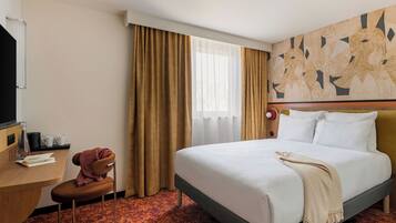 Habitación de hotel con cama, escritorio, silla, ventana con cortinas y pared con diseño geométrico.