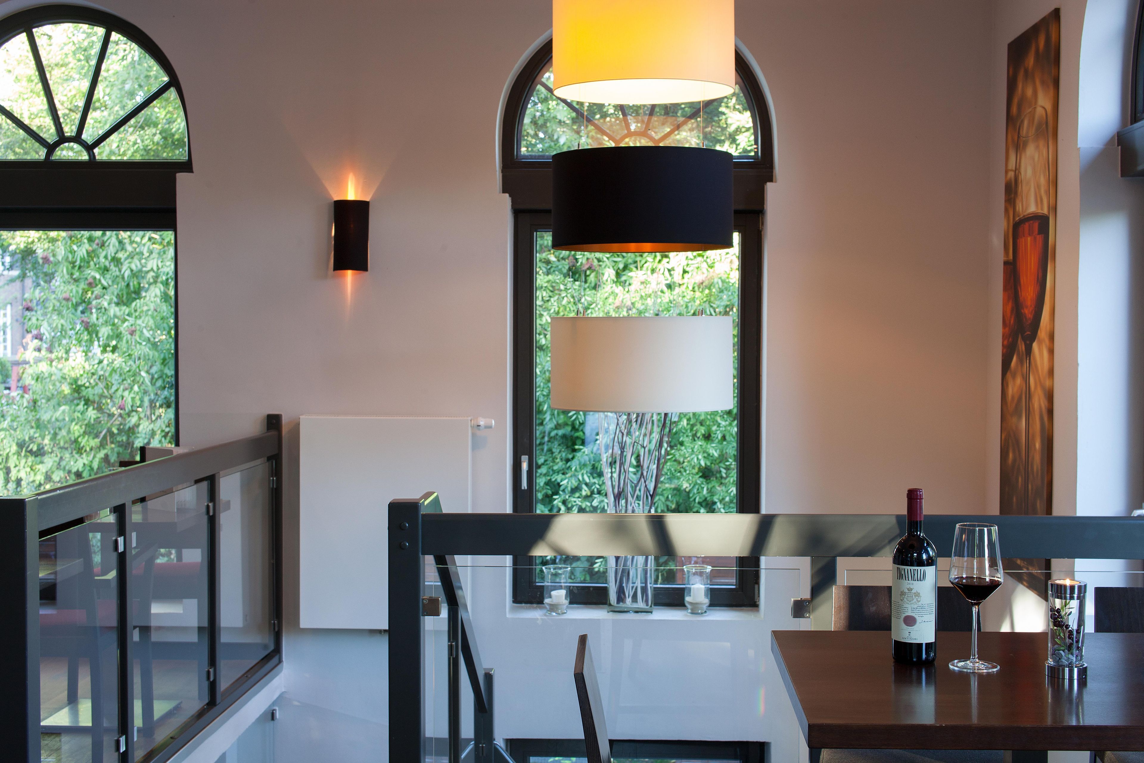 Un comedor con una mesa dispuesta para dos personas, una botella de vino y una vela sobre la mesa.