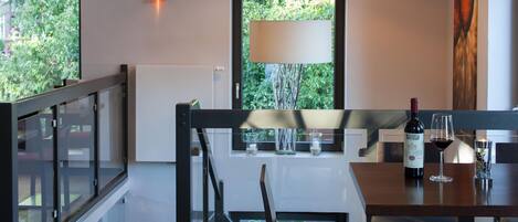 Un comedor con una mesa dispuesta para dos personas, una botella de vino y una vela sobre la mesa.