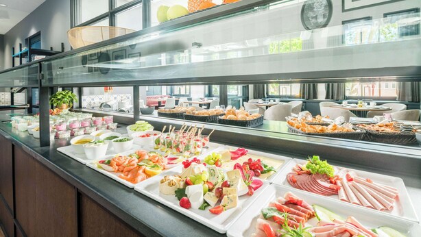 Un bufé con diversas opciones de comida, incluyendo frutas, quesos y carnes.