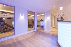 Un gimnasio moderno con paredes de espejo, equipo de ejercicio y suelo de madera.