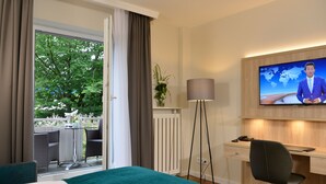 Une chambre d’hôtel équipée d’un lit, d’un bureau, d’une chaise, d’une télévision et offrant une vue sur l’extérieur.
