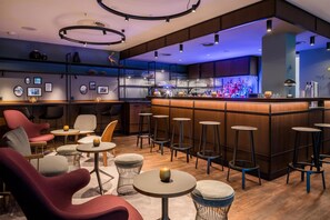 Un espace bar moderne avec des tables rondes, des tabourets de bar et un comptoir.