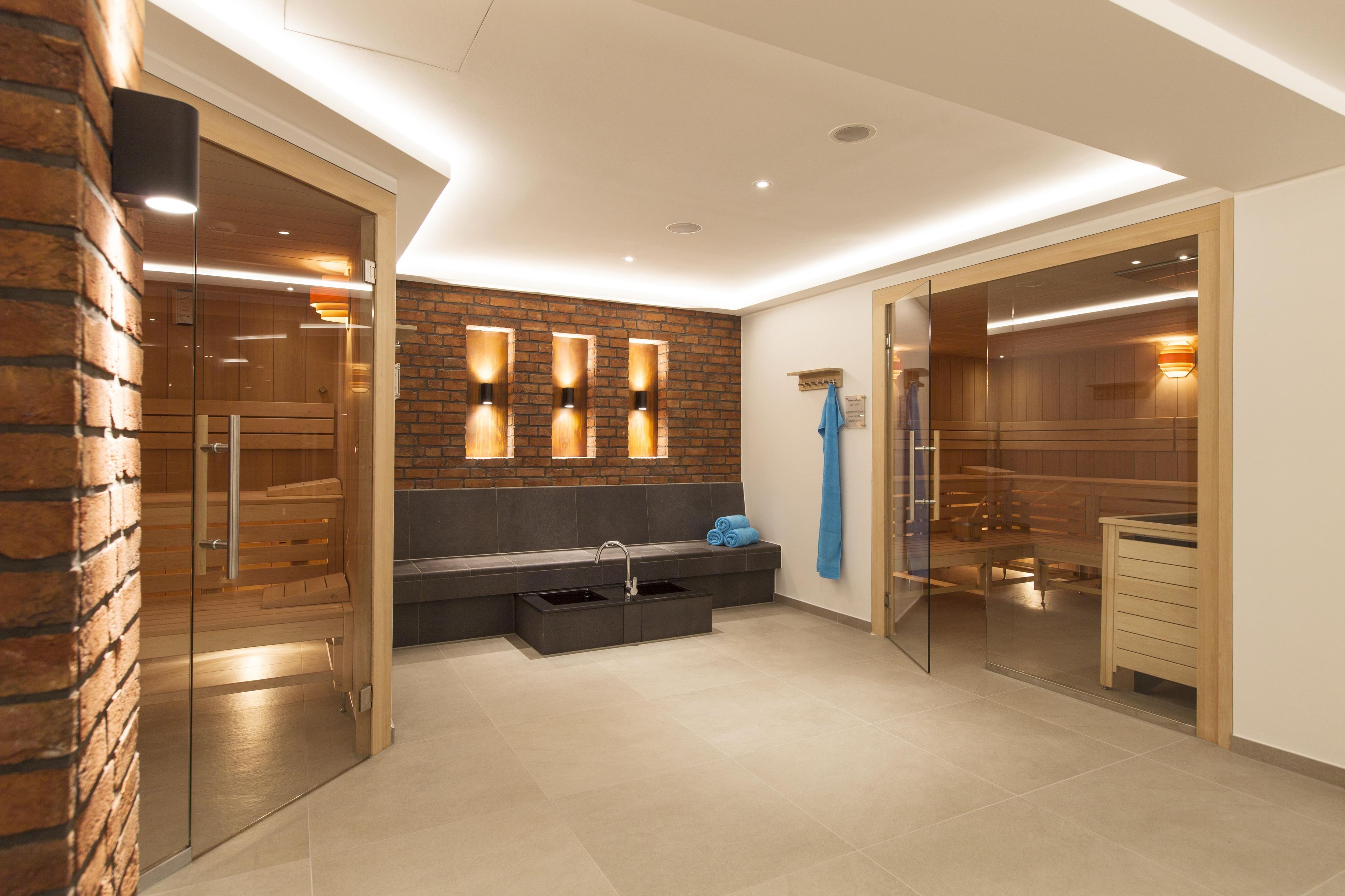 A modern bathroom with a glass shower enclosure, a bench with towels, and a wooden vanity.