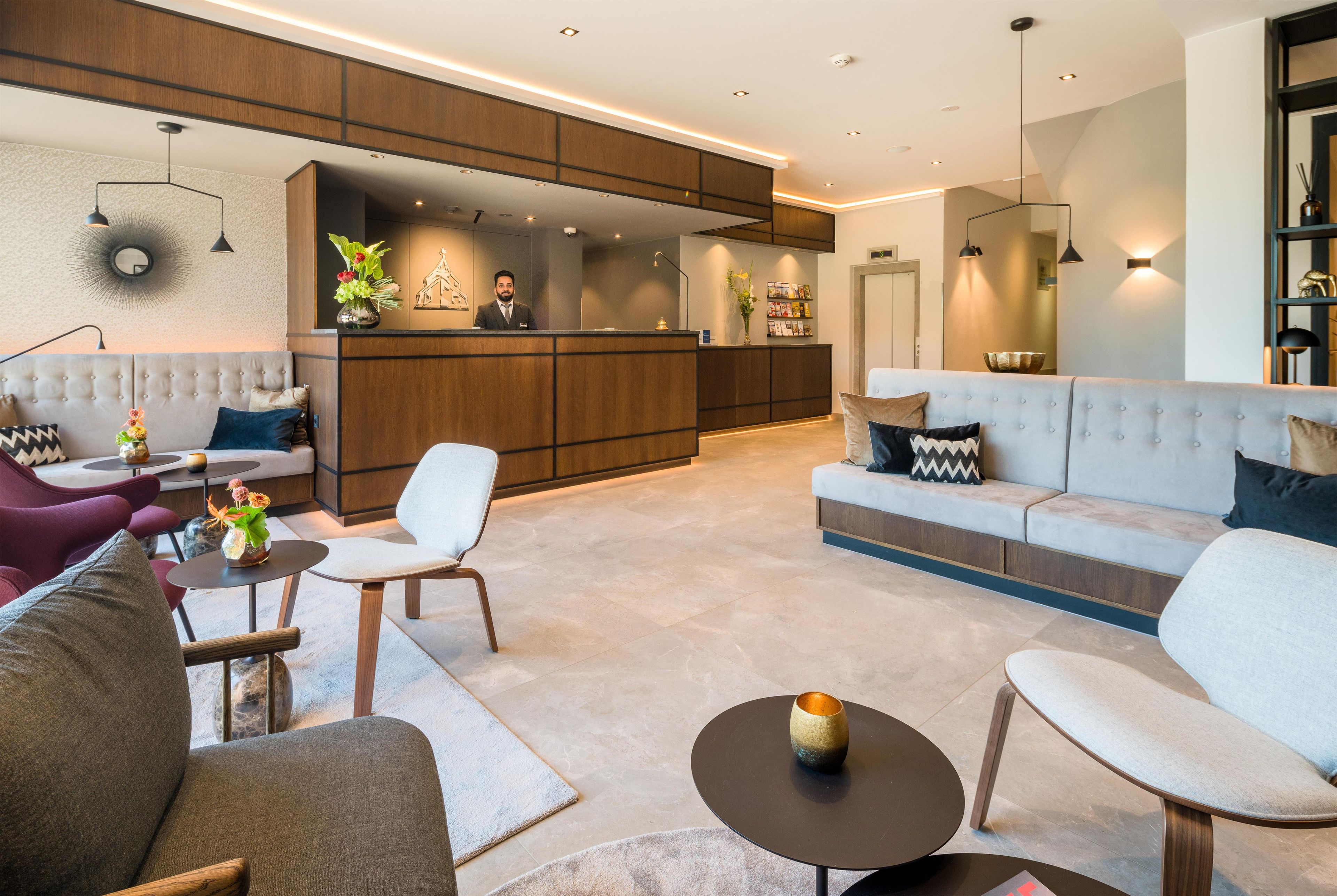 Ein modernes Wohnzimmer mit einer Couch, Sesseln, einem Couchtisch und einer Rezeption.