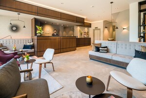 Ein modernes Wohnzimmer mit einer Couch, Sesseln, einem Couchtisch und einer Rezeption.