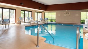 Una piscina interior con sillones de descanso y un cartel de salvavidas.