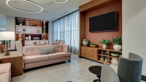 A modern living room with a sofa, chairs, a TV, and a wooden cabinet with plants.